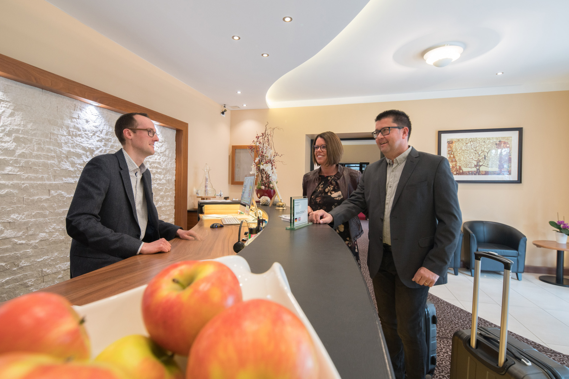 Freundlicher Empfang von Gästen an der Rezeption des Hotel Asemann in Planegg durch den Hotelier – persönlicher Service und bayerische Gastfreundschaft.