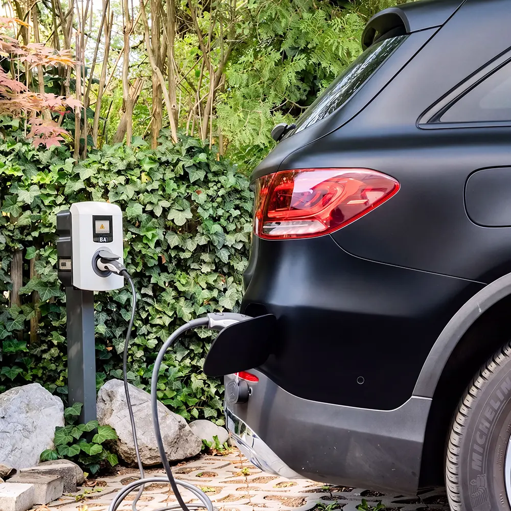 Eine moderne E-Ladestation (Wallbox) lädt ein Elektroauto auf dem Hotelparkplatz des Hotel Asemann in Planegg – umweltfreundlicher Service für Gäste.