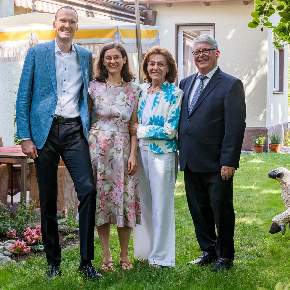 Die Gastgeberfamilie des Hotel Asemann lächelt im grünen Hotelgarten in Planegg – persönliche Führung und herzliche bayerische Gastfreundschaft.